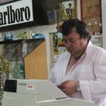 Un biglietto del Gratta e Vinci con simboli vincenti e un tabaccaio sorridente.