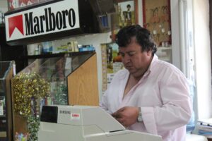 Un biglietto del Gratta e Vinci con simboli vincenti e un tabaccaio sorridente.