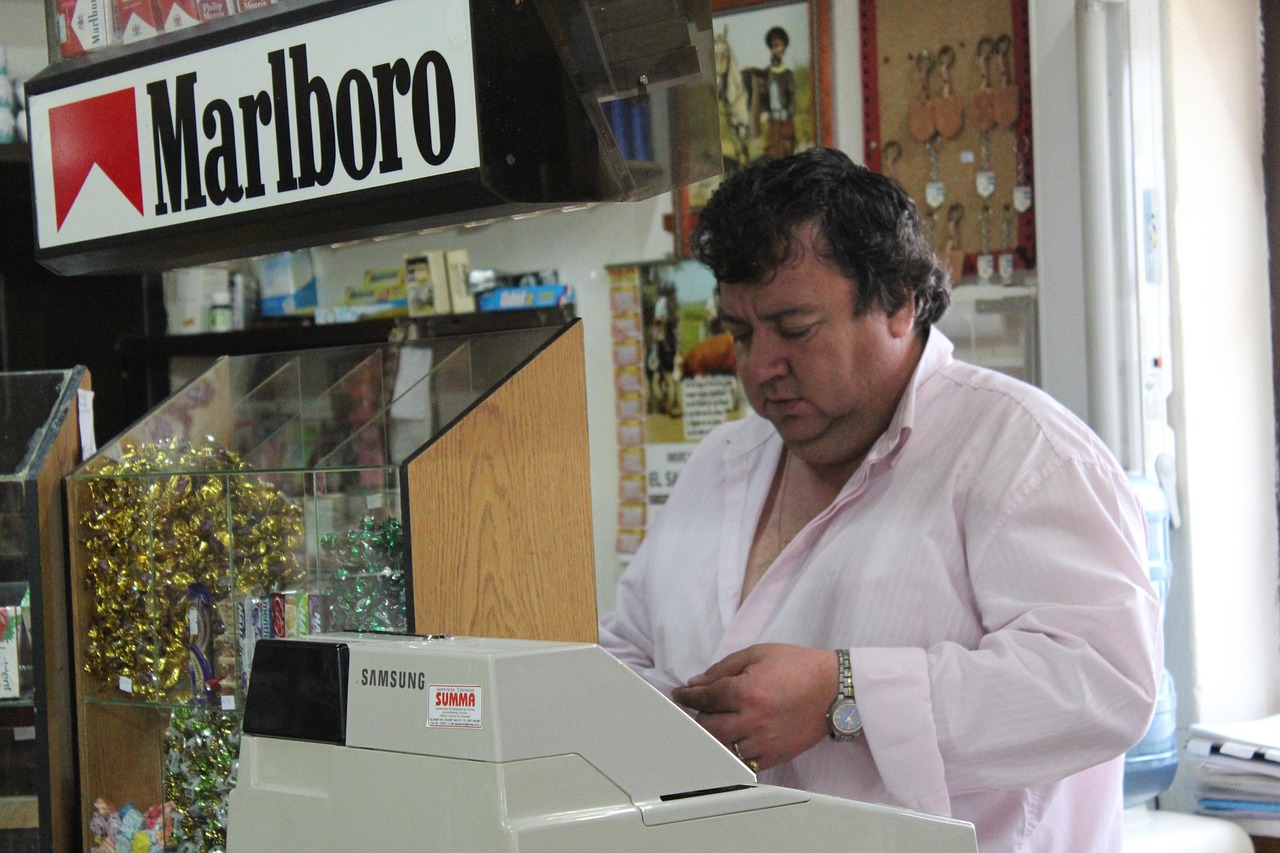 Un biglietto del Gratta e Vinci con simboli vincenti e un tabaccaio sorridente.